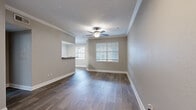 Located at 5825 Crossings Boulevard in Antioch, TN, this one-bedroom, one-bathroom residence offers a thoughtfully arranged single-floor layout. The open living area features rich wood-style flooring, crown molding, a textured ceiling, and a ceiling fan, with natural light streaming in through window blinds. A pass-through counter connects the living space to the kitchen, which is equipped with stainless steel appliances — including a refrigerator, range, microwave, and dishwasher — complemented by granite-style countertops and white cabinetry with light wood-style tile flooring. The bedroom is a comfortable, well-proportioned retreat with soft carpet, a ceiling fan, natural light from a window, and direct access to a walk-in closet outfitted with wire shelving. The full bathroom features an extended granite-topped vanity with white cabinetry, a large mirror, wood-style tile flooring, and a tiled tub-shower combination. A hallway connects the main living areas to the private bedroom wing, and a dedicated closet provides additional storage. Neutral gray tones are carried consistently throughout the space, creating a cohesive and modern aesthetic.