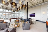 Located at 330 W Brambleton Ave in Norfolk, Virginia, this expansive amenity floor offers a comprehensive suite of lifestyle and wellness facilities spread across a generously sized single-level footprint. The space is defined by soaring ceilings, large floor-to-ceiling windows, and an industrial-modern aesthetic that blends exposed ductwork and structural elements with refined finishes.

The resident lounge serves as a social centerpiece, featuring a striking sculptural pendant ceiling installation, a billiards table, comfortable lounge seating, a bar-height counter with bar stools, and a large wall-mounted television. Abundant natural light floods the space through panoramic windows that frame elevated views of the Norfolk skyline and waterfront.

The fitness center is thoroughly equipped with a wide range of cardio machines—including treadmills, ellipticals, and rowing machines—as well as cable weight machines, free weights, and a dedicated functional training area with medicine balls and stability equipment. Large windows throughout the gym offer inspiring city views during workouts.

The indoor lap pool is a standout feature, enclosed by expansive wraparound windows that deliver unobstructed views of the Norfolk skyline and the Elizabeth River. Light wood flooring and built-in bench seating surround the pool, creating a calm, resort-like atmosphere. A clean entry corridor with tile flooring and elevator access provides a polished arrival experience to the entire floor.
