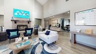 This contemporary 620 square foot space in Riverside, CA, showcases a thoughtfully designed living area and hallway. The interior is characterized by its striking high ceilings, which create a sense of spaciousness and grandeur. Large windows flood the space with natural light, enhancing the bright and airy ambiance.

The living room is the focal point, featuring a modern fireplace with a sleek mantel and a mounted flat-screen TV above. A comfortable white sofa and navy armchair provide ample seating, complemented by a stylish area rug in shades of blue and white. The room's decor is accented with touches of teal, creating a cohesive color scheme.

Adjacent to the living area, there's a small workspace with a dark wood desk and chairs, perfect for a home office or study nook. The space also includes a compact kitchenette area with white cabinetry and a tiled backsplash, ideal for light meal preparation or entertaining.

The hallway leads to other areas of the property, featuring the same light wood-look flooring that runs throughout the space. Glass-paned doors at the entrance allow additional natural light to penetrate the interior, further brightening the environment.

Overall, the space combines modern design elements with a practical layout, creating a welcoming and functional living area that maximizes its compact square footage.