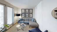 This thoughtfully designed single-floor residence offers a cohesive blend of modern aesthetics and functional living across its key spaces. The kitchen is a standout feature, showcasing crisp white cabinetry extending to the ceiling, stainless steel appliances including a gas range, microwave, and French door refrigerator, complemented by white quartz countertops, under-cabinet lighting, and a tile backsplash. Dark hardwood-style flooring runs throughout the kitchen and wet areas, adding warmth and contrast to the bright, clean palette.

The living area provides a comfortable retreat, finished with neutral carpeting and featuring a gallery wall arrangement of framed artwork that adds a curated, contemporary touch. Natural light filters in through the windows, enhancing the welcoming ambiance.

Both bedrooms are carpeted and well-lit, each with windows that invite natural light. The rooms offer ample space for furnishings and storage, maintaining the same clean, modern aesthetic found throughout the unit.

The two bathrooms are finished with attention to detail. One features full-height vertical tile surrounding a soaking tub and shower combination with built-in niche storage, while the second offers a dark-cabinet vanity with white countertops and wood-look flooring, both reflecting a polished, contemporary design sensibility.
