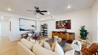 Located in Herriman, Utah, this single-floor residence on Bella Vea Drive offers a thoughtfully designed open-concept layout with clean, contemporary finishes throughout. Light hardwood-style flooring flows through the main living areas, complementing the crisp white walls and creating a bright, welcoming atmosphere.

The living room serves as the heart of the home, featuring large windows dressed with horizontal blinds that invite ample natural light. A ceiling fan with recessed lighting adds to the comfort of the space, while a wall-mounted television above a striking chevron-patterned wood media console anchors the room. The open dining area connects seamlessly to the living space, ideal for everyday living and entertaining.

The kitchen is equipped with stainless steel appliances, including a full-size refrigerator, range, and built-in microwave. Rich wood-toned cabinetry pairs with white quartz countertops, while a spacious island with an integrated double sink and bar seating adds both function and style. Pendant lighting and windows enhance the kitchen's airy feel.

The bedrooms feature plush carpeting and generous windows that fill each room with natural light. The primary bedroom includes a bank of windows for a bright, serene retreat. Both bathrooms are finished with wood-tone floating vanities, white quartz counters, light hardwood-style flooring, and tub-shower combinations, offering a clean and modern aesthetic throughout.