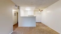 Located at 2175 S Mallul Dr in Anaheim, CA, this one-bedroom, one-bathroom residence offers a well-organized single-floor layout designed for comfortable everyday living. The entry hallway features wood-look flooring and a built-in storage cabinet with a large ventilation unit overhead, providing a clean and functional transition into the main living areas. The living room is generously proportioned, featuring plush wall-to-wall carpeting, a textured ceiling, and a ceiling fan with light fixture. A sliding glass door opens to a private balcony, framing views of lush tropical foliage and bringing in abundant natural light. The kitchen is defined by a raised pass-through counter peninsula, white upper cabinetry, and wood-look flooring, creating an open connection to the living area. The bedroom is a comfortably sized, carpeted retreat with a window that fills the room with natural light and a dedicated closet for storage. The bathroom is neatly appointed with a white vanity, speckled countertop, mirrored medicine cabinet, and a full tub-shower combination, all set on wood-look flooring. Throughout the residence, a neutral color palette of white walls and warm beige tones creates a bright, cohesive ambiance.