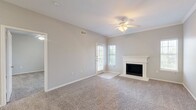 This well-appointed 2-bedroom, 2-bathroom residence is thoughtfully laid out across a single floor, offering a comfortable and functional living experience. The spacious living room serves as the heart of the home, featuring plush carpeting, crown molding, a ceiling fan, and a classic white-mantled fireplace that adds warmth and character. Natural light filters in through shuttered windows, and a door provides convenient exterior access directly from the living area. The galley-style kitchen is efficiently designed with rich dark-wood cabinetry, white countertops, tile flooring, and white appliances including a range, microwave, refrigerator, and a double sink. Built-in shelving adjacent to the kitchen adds practical storage and display space. The primary bedroom is generously sized, complete with a ceiling fan and a large window overlooking the outdoors. Both bathrooms are finished with tile flooring, dark wood vanity cabinets, white countertops, and tub/shower combinations. Two dedicated closets provide ample storage, each carpeted and fitted with hanging rods. A hallway connects the main living spaces, completing this cohesive and practical floor plan.