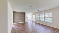 Located at 53 Sand Pit Rd in Danbury, Connecticut, this single-floor residence offers a well-designed layout with consistent hardwood-style flooring throughout and a neutral color palette that creates a bright, welcoming atmosphere. The spacious living area is a standout, anchored by a striking shiplap wood accent wall that adds a modern farmhouse character to the space. Large windows along the exterior wall flood the room with natural light and offer views of the surrounding greenery, while a glass-panel door provides additional brightness and outdoor access. The galley-style kitchen is thoughtfully appointed with crisp white shaker cabinetry, granite countertops, subway tile backsplash, and stainless steel hardware, delivering both style and functionality. The bedrooms are generously sized, each featuring hardwood-style flooring, ample natural light from well-placed windows, and closet access. The bathroom is clean and functional, finished with white tile surrounding a full soaking tub and shower combination, complemented by a white vanity and hardwood-style flooring. Textured ceilings appear throughout the unit, and the open flow between the living and dining areas enhances the overall sense of space. This residence combines practical design with modern finishes in a comfortable Danbury setting.