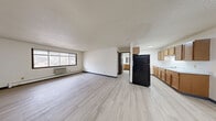 Located at 175 S National Ave in Fond du Lac, Wisconsin, this one-bedroom, two-bathroom unit offers a functional single-floor layout with a clean, neutral aesthetic throughout. Light-toned vinyl plank flooring runs continuously across all rooms, creating a cohesive and easy-to-maintain interior.

The combined kitchen and living area forms the heart of the unit. The living space is open and well-proportioned, featuring white walls, a textured ceiling, a wall-mounted air conditioning unit, and a baseboard heating system. A large picture window with a diamond-pane detail allows natural light to fill the room. The adjacent kitchen is configured as a galley, equipped with warm oak cabinetry, a light-toned countertop, a stainless single-basin sink, a white range, and a black refrigerator, offering practical storage and workspace.

The bedroom is a comfortably sized room featuring two windows that provide ample natural light and outdoor views, along with baseboard heating and a wall-mounted AC unit. Dark wood-framed doors appear consistently throughout the unit, adding a classic contrast to the bright white walls.

The two bathrooms include a full bath with a tub/shower combination and a second bath featuring an oak vanity with a large mirror and strip lighting, both finished with the same light flooring found throughout the unit.