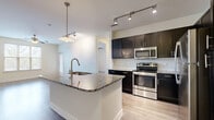 This thoughtfully designed 2-bedroom, 2-bathroom residence offers a functional and modern living experience across a single floor. The open-concept kitchen serves as the heart of the home, featuring rich dark cabinetry, granite countertops, a large center island with an undermount sink, pendant lighting, and a full suite of stainless steel appliances including a range, microwave, and refrigerator. Track lighting and wood-look flooring complete the kitchen's contemporary aesthetic.

The living area flows naturally from the kitchen, offering a comfortable and versatile space. The primary bedroom is generously sized, featuring wood-look flooring, a ceiling fan, and a large window that fills the room with natural light. The second bedroom is finished with plush carpeting and its own window with blinds. Both bedrooms provide a calm, neutral palette.

The two bathrooms are consistently finished with granite-topped dark vanities, tile flooring, and tub-shower combinations. The primary bath features a dual-sink vanity, adding convenience and functionality.

Additional highlights include a hallway connecting the private areas, a dedicated closet for storage, and ceiling fans in the bedrooms for year-round comfort. The consistent use of neutral tones and quality finishes throughout creates a cohesive and inviting living environment.