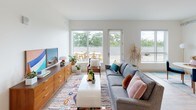 Located at 621 Lake Michigan Dr NW in Grand Rapids, Michigan, this single-floor unit blends modern design with industrial-chic details to create a bright, cohesive living space. Exposed ductwork runs along the ceilings throughout, adding an urban loft character that complements the clean white walls and light hardwood-style flooring found in the main living areas.

The living room is generously proportioned, featuring large windows and a glass patio door that flood the space with natural light and provide views of lush greenery and an outdoor patio area. The open layout flows comfortably, offering room for distinct seating and lounging arrangements.

The kitchen is well-appointed with rich dark cabinetry, granite countertops, stainless steel appliances, and light wood-tone flooring. Ample counter space on both sides creates a functional galley-style layout suited for everyday cooking.

The bedroom features plush carpeting, a sizable window overlooking the outdoor patio, and exposed ductwork that continues the industrial aesthetic. The room receives strong natural light and offers pleasant outdoor views.

The bathroom is clean and functional, featuring tile flooring, a granite-topped vanity with a large mirror, and a walk-in shower. Overall, the unit presents a cohesive, contemporary aesthetic with thoughtful design details throughout.
