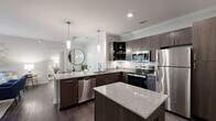 Located in Daphne, Alabama, this well-appointed 2-bedroom, 2-bathroom single-story home offers a thoughtfully designed layout with modern finishes throughout. Dark wood-style flooring flows seamlessly across the living spaces, complemented by neutral gray walls and ceiling fans in every room.

The open-concept kitchen is a standout feature, showcasing granite countertops, dark espresso cabinetry, a subway tile backsplash, stainless steel appliances, and pendant lighting — ideal for both everyday cooking and entertaining. The adjacent living room is bright and welcoming, with crown molding, large windows, and French doors that open to a private balcony, filling the space with natural light.

The primary bedroom is generously sized with a ceiling fan, walk-in closet, and a dedicated en-suite bathroom featuring a tub/shower combo, granite vanity, and dark wood cabinetry. The second bedroom also includes a ceiling fan and direct closet access. Both bathrooms are finished with clean, bright fixtures and tub/shower combinations.

Additional highlights include a utility room, hallway, and ample closet storage. The consistent use of neutral tones and quality materials throughout gives the home a cohesive, modern aesthetic suited for comfortable everyday living.