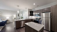 Located in Daphne, Alabama, this well-appointed 2-bedroom, 2-bathroom single-story home offers a thoughtfully designed layout with modern finishes throughout. Dark wood-style flooring flows seamlessly across the living spaces, complemented by neutral gray walls and ceiling fans in every room.

The open-concept kitchen is a standout feature, showcasing granite countertops, dark espresso cabinetry, a subway tile backsplash, stainless steel appliances, and pendant lighting — ideal for both everyday cooking and entertaining. The adjacent living room is bright and welcoming, with crown molding, large windows, and French doors that open to a private balcony, filling the space with natural light.

The primary bedroom is generously sized with a ceiling fan, walk-in closet, and a dedicated en-suite bathroom featuring a tub/shower combo, granite vanity, and dark wood cabinetry. The second bedroom also includes a ceiling fan and direct closet access. Both bathrooms are finished with clean, bright fixtures and tub/shower combinations.

Additional highlights include a utility room, hallway, and ample closet storage. The consistent use of neutral tones and quality materials throughout gives the home a cohesive, modern aesthetic suited for comfortable everyday living.