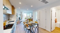 This thoughtfully designed one-bedroom, one-bathroom unit makes excellent use of its compact footprint across a single floor. The open-plan layout seamlessly connects the kitchen, dining, and living areas, creating a cohesive and functional living space filled with natural light.

The kitchen features a clean, contemporary design with warm wood upper cabinetry, white lower cabinets, light quartz countertops, a grey tile backsplash, and stainless steel appliances including a range and dishwasher. A dining area with a dark-topped table and mixed seating sits adjacent to the kitchen, ideal for everyday meals or entertaining.

The living room is anchored by large floor-to-ceiling windows that frame sweeping views of lush, tree-covered hillsides, flooding the space with natural light. Light wood laminate flooring runs throughout, tying the common areas together with a warm, modern aesthetic.

The bedroom continues the airy feel with oversized windows offering panoramic treetop and open-sky views, providing a bright and tranquil retreat. The bathroom is finished in a clean, minimalist style with wood-toned cabinetry, white countertops, a soaking tub with shower, and crisp white walls. Recessed lighting throughout the unit completes the polished, modern feel.