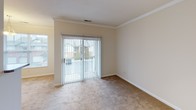 This single-story, one-bedroom, one-bathroom unit offers a thoughtfully organized layout across a comfortable footprint. The living area is finished with plush wall-to-wall carpeting and accented by crown molding along the ceiling, lending a polished touch to the space. A sliding glass door floods the room with natural light while providing direct views of the surrounding exterior. An additional window further enhances the brightness of the living area.

The galley-style kitchen is efficiently designed, featuring warm wood cabinetry, dark granite-style countertops, and stainless steel appliances including a range, microwave, and refrigerator. Wood-look flooring runs through the kitchen, adding warmth and contrast. A pass-through connects the kitchen to the living and dining area, creating an open, communicative feel between spaces.

The bedroom is generously sized with soft carpeting, a walk-in closet with built-in shelving, and direct access to the full bathroom. The bathroom includes a tiled tub-shower combination and wood-look flooring. A dedicated entry area with a full-panel door completes the unit's practical layout.