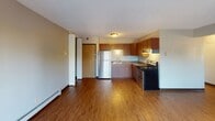 Located at 1118 28th Ave S in Grand Forks, North Dakota, this single-floor residence offers a practical and comfortable layout with a variety of well-maintained spaces throughout. The living area features durable hardwood-style flooring, textured ceilings, and sliding glass doors dressed with vertical blinds that open to a private outdoor balcony, allowing natural light to fill the room. Baseboard heating is present throughout the unit, ensuring consistent warmth during North Dakota winters. The kitchen is equipped with warm-toned wood cabinetry, dark granite-style countertops, a double-basin stainless steel sink with under-cabinet lighting, a stainless steel refrigerator, and a black gas range, providing ample storage and functionality for everyday cooking. The bedrooms are carpeted for comfort and feature natural light through wood-trimmed windows with outdoor views, along with built-in closets offering organized storage space. The bathroom is neatly appointed with a dark-finished vanity, a framed mirror with overhead lighting, and a full tub-shower combination with brushed nickel fixtures. Throughout the residence, neutral wall tones and consistent finishes create a cohesive and move-in ready atmosphere suited for comfortable everyday living.
