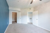 This single-floor residence offers a thoughtfully designed open-concept layout that seamlessly connects the living, dining, and kitchen areas. The living space is anchored by a bold teal accent wall that adds a striking pop of color, complemented by wood-look plank flooring and crown molding throughout. A ceiling fan provides both function and style in the main living area.

The kitchen is outfitted with white cabinetry, dark countertops, and stainless steel appliances, including a refrigerator, range, and microwave. A breakfast bar peninsula separates the kitchen from the living area, creating a natural flow for everyday living and entertaining.

The bedrooms feature plush carpeting and teal accent walls, contributing to a cohesive design theme. The primary bedroom is generously sized, complete with a ceiling fan and a walk-in closet equipped with built-in shelving. A secondary bedroom offers natural light through a window with vertical blinds.

The bathroom includes white cabinetry with dark countertops, a shower-tub combo, and wood-look flooring. A dedicated in-unit laundry area with a full-size washer and dryer hookup and overhead shelving adds everyday convenience to this well-rounded residence.