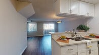 Located on Crenshaw Boulevard in the Mid-City neighborhood of Los Angeles, this two-story residence offers a thoughtfully designed layout across two levels. The main living area features rich, dark hardwood-style flooring that extends throughout, complemented by soft neutral-toned walls and a textured ceiling. Large sliding glass doors and windows fitted with vertical blinds allow generous natural light to fill the space, creating a bright and open atmosphere.

The kitchen is efficiently arranged in a galley configuration and opens to the living area via a peninsula counter with light stone-toned surfaces and white cabinetry equipped with brushed nickel hardware. Stainless steel appliances, including a gas range, microwave, dishwasher, and refrigerator, provide a modern, functional workspace.

The bedrooms are carpeted for comfort and each features sliding glass doors that open to outdoor access, along with mirrored closets offering practical storage. Two bathrooms serve the residence; one includes a full tub-shower combination with brushed nickel fixtures and hardwood-style flooring, while the second features a vanity with ample counter space. A staircase connects the two floors, completing this well-appointed urban home.