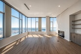 This sophisticated high-rise residence exemplifies modern urban living through its clean architectural lines, premium finishes, and abundant natural light. Warm hardwood flooring flows throughout the open-plan layout, seamlessly connecting the living and kitchen areas.

The chef's kitchen is a standout centerpiece, featuring a generous island with a crisp white quartz countertop, a gas cooktop, a large stainless steel range hood, integrated panel-ready refrigerator, double wall ovens, and custom wood-grain cabinetry. A dedicated wine cooler adds a refined touch to the entertaining space.

Floor-to-ceiling windows frame breathtaking panoramic views of the city skyline and waterfront, flooding every room with natural light. The bedrooms are well-proportioned and sun-drenched, while the primary suite includes an expansive walk-in closet outfitted with custom dark wood shelving, hanging rods, and built-in drawers.

The bathrooms are finished to a spa-like standard, with stone tile flooring, a freestanding soaking tub positioned to capture waterfront views, a glass-enclosed shower, and a floating vanity with an illuminated mirror. A dedicated in-unit laundry room with a full-size washer and dryer adds everyday convenience to this refined urban residence.