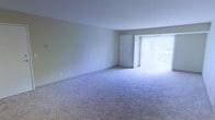 This single-floor residence offers a clean, functional layout designed to maximize comfort and usability. The main living area is generously proportioned, featuring wall-to-wall carpeting in a neutral tone that adds warmth and softness underfoot. Smooth, light-colored walls complement the bright white ceiling, creating a calm and airy atmosphere throughout the space.

A standout feature of the living area is the large sliding glass door dressed with vertical blinds, which floods the room with natural light and provides direct access to an outdoor area. This connection to the exterior enhances the overall sense of openness. A secondary interior door is also present, offering access to an adjacent room or closet space.

The overall design is straightforward and neutral, making it highly adaptable to a variety of furnishing styles and personal aesthetics. The absence of clutter and the simplicity of the finishes give the space a clean, move-in-ready appeal. The single-floor layout ensures easy navigation throughout, making it a practical and comfortable living environment.