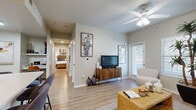 This 2-bedroom, 1-bathroom residence is designed for comfortable, efficient living across a single floor. Light wood-style flooring runs continuously throughout, creating a cohesive and airy feel from room to room. The living room serves as the heart of the home, featuring a ceiling fan, natural light from windows with exterior views, and direct sightlines through to the hallway and bedrooms — making the space feel open and connected. Adjacent to the living area, the kitchen is equipped with white shaker-style cabinetry, light quartz countertops, a classic white subway tile backsplash, open shelving, and stainless steel appliances, offering both style and practicality. A hallway connects the main living areas to the two bedrooms, each featuring ceiling fans, windows with natural light, and hardwood-style flooring. The primary bedroom offers a comfortable footprint with vaulted ceiling details and wall space suited for artwork. The second bedroom mirrors a similar layout with its own ceiling fan and window. The shared bathroom includes a white vanity with quartz countertops, a large mirror, and a full tub-shower combination. A dedicated walk-in closet with wire shelving provides ample storage. The overall ambiance is clean, neutral, and move-in ready.