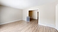 This well-appointed two-story home in Memphis, Tennessee offers three bedrooms, four bathrooms, and a thoughtfully organized layout spread across two floors. The main level features a welcoming living room anchored by a classic brick fireplace with a white mantel and complemented by wood-look vinyl flooring and vertical-blind sliding glass doors that invite natural light. Adjacent vertical shiplap-style wall paneling adds a distinctive architectural touch. The combined dining room and kitchen is outfitted with white cabinetry, light countertops, and black appliances, including a range and dishwasher, over durable hardwood-style flooring. A separate den provides additional flexible living space. Upstairs, the generously sized primary bedroom features plush carpeting, a walk-in closet, and a private en-suite bathroom with a vanity and tub-shower combination. Two additional carpeted bedrooms offer ample natural light through large windows, with convenient access to shared bathrooms featuring tub-shower combos and granite-style countertop vanities. Five closets throughout the home ensure abundant storage. A dedicated laundry area and two staircases complete this practical and comfortable layout.