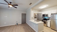 This well-appointed 1-bedroom, 1-bathroom unit in Baton Rouge, Louisiana offers a thoughtfully designed single-floor layout that maximizes both comfort and functionality. Throughout the space, light wood-style luxury vinyl plank flooring creates a clean, cohesive look, complemented by soft neutral wall tones and crisp white trim with crown molding accents.

The open living area is bright and airy, featuring ceiling fans with integrated lighting and French doors that lead to a private balcony, allowing natural light to flow freely into the space. A secondary window further enhances the sense of openness.

The kitchen is equipped with stainless steel appliances, including a refrigerator, electric range, and over-the-range microwave. White shaker-style cabinetry provides generous storage, while a light quartz peninsula with an undermount sink serves as a natural divider between the kitchen and living area. A washer and dryer are conveniently located just off the kitchen.

The bedroom is a comfortable retreat, featuring a ceiling fan, a large window with natural light, and ample wall space. The full bathroom includes a vanity with quartz countertop, a tub/shower combination with tile surround, and clean, bright finishes throughout. This unit offers a practical and modern living experience in a convenient Baton Rouge location.