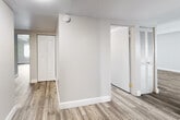 This single-floor residence offers a practical and comfortable layout with consistent wood-style flooring running throughout the entire unit. The open living and dining area is generously proportioned, featuring exposed beam ceilings with a textured finish and a sliding glass door that fills the space with natural light. A dedicated hallway connects the living areas to the private quarters, with a closet and additional storage conveniently accessible along the way.

The galley-style kitchen is efficiently designed, lined on both sides with dark gray cabinetry and light stone-finish countertops. A stainless steel double-basin sink, black appliances including a gas range and refrigerator, and a white brick accent wall give the kitchen a clean, functional character. Recessed lighting provides ample illumination throughout.

The bedrooms are well-sized and bright, each featuring the same wood-style flooring and windows fitted with vertical blinds that offer views of surrounding greenery. Exposed ceiling beams echo the design language found in the main living area.

The bathrooms are thoughtfully appointed, with one featuring a sliding-door stand-up shower and a vanity with dark cabinetry and a single sink, while another includes a full soaking tub with classic white tile surround. The overall ambiance of the unit is clean, neutral, and move-in ready.