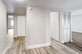 This single-floor residence offers a practical and comfortable layout with consistent wood-style flooring running throughout the entire unit. The open living and dining area is generously proportioned, featuring exposed beam ceilings with a textured finish and a sliding glass door that fills the space with natural light. A dedicated hallway connects the living areas to the private quarters, with a closet and additional storage conveniently accessible along the way.

The galley-style kitchen is efficiently designed, lined on both sides with dark gray cabinetry and light stone-finish countertops. A stainless steel double-basin sink, black appliances including a gas range and refrigerator, and a white brick accent wall give the kitchen a clean, functional character. Recessed lighting provides ample illumination throughout.

The bedrooms are well-sized and bright, each featuring the same wood-style flooring and windows fitted with vertical blinds that offer views of surrounding greenery. Exposed ceiling beams echo the design language found in the main living area.

The bathrooms are thoughtfully appointed, with one featuring a sliding-door stand-up shower and a vanity with dark cabinetry and a single sink, while another includes a full soaking tub with classic white tile surround. The overall ambiance of the unit is clean, neutral, and move-in ready.