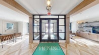 Oxbow's amenity space is designed with a contemporary aesthetic that blends clean architectural lines with warm, inviting finishes throughout. The grand entrance lobby greets visitors with floor-to-ceiling black-framed glass doors, light wood geometric-patterned flooring, and a signature branded welcome mat, setting an upscale tone from the moment of arrival.

The open-plan social hub features soaring vaulted ceilings and an abundance of natural light pouring through large black-framed windows. A spacious communal workspace with a live-edge wood table provides an ideal setting for collaboration, while an adjacent lounge area offers comfortable seating with navy accent walls, built-in window benches, and curated décor. A fully equipped demonstration kitchen showcases slate-blue cabinetry, open plate rack shelving, a professional-grade gas range, and a handcrafted zellige tile backsplash.

The expansive fitness center is outfitted with a comprehensive selection of cardio and strength-training equipment, floor-to-ceiling mirrors, and large windows overlooking the surrounding community. A dedicated spin studio with Peloton bikes and glass partition walls provides a focused space for cycling workouts. Together, these amenities create a well-rounded, resort-style environment built for community, wellness, and everyday living.