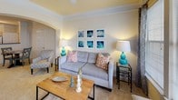 This single-floor residence offers a thoughtfully designed layout that maximizes comfort and functionality. The living room serves as the heart of the home, featuring a tray ceiling with crown molding, a ceiling fan, and an elegant arched entryway. Large windows flood the space with natural light and provide pleasant outdoor views, creating a bright and welcoming atmosphere with soft carpeting underfoot.

The kitchen is well-equipped with light wood cabinetry, dark countertops, white appliances including a range and refrigerator, and wood-look flooring. A peninsula with an additional sink adds extra workspace and casual dining potential. Track lighting overhead ensures the space is well-lit. A dedicated laundry area is conveniently accessible from within the unit.

The bedroom is a comfortable retreat featuring plush carpet, a window with decorative curtains, and direct access to the bathroom. The full bathroom includes a soaking tub with shower, wood-look tile flooring, and a walk-in closet, providing ample storage. Crown molding adds a refined touch throughout the home, tying together the warm, neutral color palette that lends a cohesive and inviting feel to the entire residence.