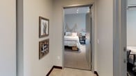 Located at 2615 S King St in Honolulu, Hawaii, this single-floor unit offers a thoughtfully designed layout well-suited for shared living. The kitchen is a standout feature, showcasing rich wood-grain cabinetry extending from floor to ceiling, white quartz countertops, stainless steel appliances including a refrigerator, dishwasher, and microwave, and under-cabinet lighting that creates a warm, functional workspace.

The bedrooms are carpeted and finished with soft grey walls, providing a calm and comfortable environment. Each room is equipped with individual study desks, chairs, and open wardrobe units for organized storage. Wall-mounted mini-split air conditioning units ensure year-round climate control. Select bedrooms benefit from large windows that invite natural light and offer views of the surrounding Honolulu cityscape and distant hills.

The bathrooms feature concrete-style flooring, wood-grain vanities with white basin sinks, and shower-tub combinations with classic curtain enclosures. A shared hallway connects the rooms, decorated with Hawaii-themed artwork that reflects the local culture. The overall aesthetic is modern and cohesive, blending practical design with subtle island-inspired touches throughout.