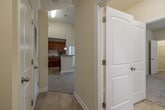 This single-floor residence offers a thoughtfully designed layout that balances comfort and functionality throughout. The kitchen serves as a central highlight, showcasing rich warm-toned wood cabinetry topped with crown molding, granite-style countertops, a peninsula island ideal for casual dining or meal prep, pendant lighting, and black appliances including a refrigerator, range, microwave, and dishwasher. Tile flooring runs throughout the kitchen, adding a clean, durable finish.

The living area impresses with soaring vaulted ceilings that amplify the sense of space, complemented by soft neutral carpeting and a large window that floods the room with natural light and provides views of the surrounding neighborhood. An arched alcove adds an architectural touch, creating a naturally defined nook within the open layout.

The bedrooms are carpeted and generously proportioned, with clean neutral walls and multiple doorways providing access to hallways and closets. The bathroom is well-appointed, featuring warm wood cabinetry with granite countertops, a large vanity mirror, tile flooring, and a shower-tub combination. Throughout the residence, white paneled doors, clean baseboards, and a consistent warm beige color palette contribute to a cohesive and inviting atmosphere.