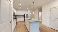Located at 11310 Vandelay Court in Charlotte, NC, this single-floor residence combines modern design with functional living. The open-concept kitchen is a standout feature, showcasing crisp white cabinetry, granite countertops, a large central island with an integrated sink, stainless steel appliances, a tiled backsplash, and elegant pendant lighting — all set atop light wood-style flooring that carries throughout the main living areas.

The living room is generously proportioned, bathed in natural light through multiple large windows and glass French doors that open to a private balcony with views of lush greenery. A ceiling fan adds to the room's comfort and airy feel.

The bedrooms feature plush carpeting, ceiling fans, and wide windows that frame tranquil outdoor views, creating bright and comfortable retreats. The primary bathroom offers a granite-topped vanity with white cabinetry, a glass-enclosed shower, and direct access to a spacious walk-in closet with built-in shelving. A secondary bathroom mirrors the same refined aesthetic with a granite vanity, soaking tub, and clean white finishes throughout.

The consistent use of light tones, quality materials, and abundant natural light gives this Charlotte residence a fresh, welcoming, and contemporary character.