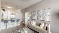 Located at 807 S Post Oak Ln in Houston's prestigious Galleria corridor, this single-floor, 2-bedroom, 2-bathroom residence offers a thoughtfully designed layout that balances comfort and style. The open-concept living and dining area is anchored by rich hardwood-style flooring, soaring walls, and a wall of large windows dressed with sheer curtains that flood the space with natural light and offer views of the surrounding cityscape. A ceiling fan adds to the airy ambiance.

The kitchen is a standout feature, boasting white cabinetry, a mosaic tile backsplash, dark granite countertops, stainless steel appliances, and a breakfast bar with pendant lighting — ideal for both casual dining and entertaining. The combined living and dining area flows seamlessly from this culinary space.

The spacious primary bedroom features plush carpeting, a ceiling fan, generous windows with urban views, and direct access to a walk-in closet with wire shelving. The en-suite bath includes a glass-enclosed walk-in shower with large-format tile. The second bedroom is equally comfortable with soft carpeting and ample closet space. Four closets in total provide exceptional storage throughout. Neutral tones and clean finishes lend the entire residence a modern, polished character.