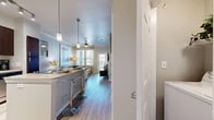 This thoughtfully designed one-bedroom, one-bathroom residence offers a functional and stylish layout across a single floor. The open-concept kitchen and living area serves as the heart of the home, where rich dark-wood cabinetry pairs with granite countertops, stainless steel appliances, and a kitchen island with bar seating — all illuminated by elegant pendant lighting and track fixtures. Light wood-style flooring runs throughout the main living areas, lending warmth and cohesion to the space.

The living room is bright and inviting, featuring crown molding, a ceiling fan, and large windows that draw in natural light while offering views of the outdoors. A private door provides direct access to a balcony, extending the living space outward.

The spacious primary bedroom is carpeted for comfort and includes generous natural light through large windows dressed with decorative curtains and blinds. A ceiling fan adds to the room's comfort, and direct access to the bathroom and closet enhances everyday convenience.

The bathroom is finished with wood-look flooring, a bold navy vanity with a granite countertop, and a shower with curtain enclosure. A dedicated closet and hallway complete the layout, providing ample storage and a smooth flow throughout this well-organized residence.