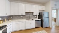 Located at 389 Plano Road in Bowling Green, Kentucky, this well-appointed 2-bedroom, 2-bathroom residence offers a clean, modern aesthetic across a single floor. The open-concept kitchen and living area serves as the heart of the home, featuring white shaker cabinetry, quartz countertops, a tiled backsplash, stainless steel appliances, and a contrasting island with additional storage. Light wood-look flooring flows throughout the main living areas, complementing the bright, neutral color palette. The living room is filled with natural light from large windows with exterior views, and is equipped with a ceiling fan for added comfort. A glass-panel entry door provides convenient outdoor access. The spacious primary bedroom features plush carpeting, a ceiling fan, large windows, and a dedicated walk-in closet with wire shelving. Its en-suite bathroom boasts a double-sink vanity with white cabinetry, quartz countertops, a glass-enclosed shower, and wood-look flooring. The second bedroom is equally comfortable with soft carpeting and its own walk-in closet. The second bathroom includes a single vanity, tub-shower combo with tile surround, and coordinating finishes. Both closets feature built-in wire shelving for organized storage throughout.
