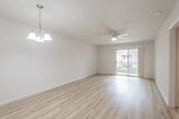 This single-floor unit offers a clean, modern aesthetic characterized by light hardwood flooring that runs seamlessly throughout the main living areas and bedrooms. The open layout connects the kitchen to the living space, creating an airy, functional flow. The living area is highlighted by a ceiling fan with integrated lighting and a sliding glass door that opens to a private balcony, allowing natural light to fill the space and providing outdoor views.

The kitchen is well-appointed with white shaker-style cabinetry featuring matte black hardware, granite countertops, a classic white subway tile backsplash, and black appliances including a gas range and full-size refrigerator. A peninsula counter area connects the kitchen to the adjoining space, offering additional prep or seating potential.

The bedroom features its own ceiling fan, a sliding closet with a built-in rod for ample storage, and a window that brings in natural light. A pendant light fixture adds a decorative touch to the dining area. The bathroom is finished with large-format tile in the tub-shower combination, sliding glass doors with brushed nickel hardware, and coordinating tile flooring. Throughout the unit, crisp white walls and consistent flooring create a cohesive, neutral palette.