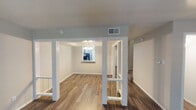 Located at 2825 W Walnut Hill Ln in Irving, Texas, this two-story space offers a well-organized layout with distinct living, dining, kitchen, and bedroom areas across both levels. The main living area features wood-style plank flooring and is defined by white structural columns that frame the transition into the dining space. The dining area is illuminated by a chandelier and benefits from natural light through a window, creating a welcoming atmosphere that connects visually to the kitchen.

The kitchen is equipped with white cabinetry, light granite-style countertops, black appliances including a range and refrigerator, and a mosaic tile backsplash that adds a decorative accent. Wood-style flooring continues throughout, and a window provides additional natural light.

The bedrooms are carpeted and feature ceiling fans with light fixtures, along with windows fitted with blinds. At least one bedroom includes a closet. The bathrooms include a full tub-and-shower combination with tiled surround, and a vanity bathroom with a framed mirror, a single-basin sink, and under-sink cabinetry with a light granite-style countertop. Overall, the space presents a clean, neutral palette throughout.