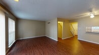 This three-floor residence offers a well-organized layout with consistent, practical finishes throughout. The main living area greets visitors with warm wood-look flooring and neutral beige walls, creating an open and inviting atmosphere. A staircase connects the main entry level to the upper floors, and a ceiling fan provides additional comfort in the living space, which also features a sliding door with vertical blinds offering access to the outdoors.

The kitchen is efficiently designed with warm oak cabinetry, white subway tile backsplash, granite-look countertops, and a full suite of white appliances including a range and dishwasher — all set on wood-look flooring.

The bedrooms are carpeted and feature ceiling fans, neutral walls, and ample natural light through blinded windows, creating calm and restful environments. The bathroom is well-appointed with a wide vanity, wood cabinetry, a large mirror with overhead lighting, and a full tub-shower combination set on hardwood-style flooring.

The lower level provides a generously sized bonus room with wood-look flooring, panel-accented walls, and small windows allowing in natural light — ideal for use as a recreation room, home office, or additional living space. Textured ceilings are present throughout the home, adding a classic residential character to every room.