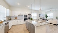 This two-story home is thoughtfully designed across a spacious main floor and a well-proportioned upper level, providing ample room for comfortable living. The open-concept kitchen and living area anchors the main floor, featuring white shaker cabinetry, granite countertops, stainless steel appliances, and a two-toned center island with pendant lighting overhead. Light wood-look flooring runs throughout, complementing the bright, neutral palette. Large windows fitted with blinds allow generous natural light to fill the living area, which is further enhanced by vaulted ceilings that lend a sense of openness.

The three bedrooms are carpeted and well-sized, including a generously proportioned primary suite with a ceiling fan, a walk-in closet with built-in shelving and hanging rods, and an en-suite bathroom boasting dual sinks set in granite countertops atop gray cabinetry. Additional bedrooms offer ample natural light and closet access. The three bathrooms maintain a consistent, clean aesthetic throughout.

An attached garage with an automatic opener provides secure parking and additional storage. A covered rear patio overlooks a fenced yard with views of the surrounding landscape, completing this functional and well-finished home.