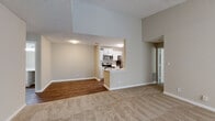This single-floor residence offers a thoughtfully designed layout that balances comfort and functionality throughout. The spacious living area greets you upon entry, featuring soft neutral carpeting, a ceiling fan, and a broad window that invites natural light to fill the room. A seamless transition leads into the kitchen, which is open to the living space via a peninsula counter. The kitchen is equipped with stainless steel appliances — including a refrigerator, range, and microwave — paired with crisp white cabinetry, quartz countertops, and wood-look flooring that adds warmth and easy maintenance underfoot. The layout continues into a dedicated corridor connecting the private areas of the home. Multiple bedrooms offer generous proportions, plush carpeting, neutral wall tones, and windows overlooking greenery outside, creating a calm and restful atmosphere. The bathrooms are finished with clean white vanities topped with quartz countertops, undermount sinks, brushed nickel hardware, and a tub-shower combination, conveying a fresh, updated aesthetic. Throughout the residence, consistent use of neutral tones, textured ceilings, and white trim details creates a cohesive and move-in-ready environment suited for a variety of lifestyles.