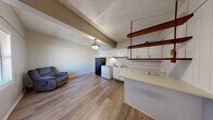 Located at 51000 County Road 512 in Sidon, Mississippi, this single-floor, one-bedroom, one-bathroom home offers a straightforward and functional layout. The interior features wood-look laminate flooring throughout, providing a cohesive and easy-to-maintain surface across all rooms.

The open-concept living and kitchen area forms the heart of the home. The kitchen is equipped with white cabinetry, a white electric range, a black refrigerator, and a single-basin sink, all arranged efficiently along one wall. A pendant light fixture hangs overhead, illuminating the combined living space, which offers enough room for casual seating.

The bedroom is generously sized relative to the overall footprint of the home, featuring vertical wood-panel accent walls painted white, a ceiling fan with light fixture, a wall-mounted air conditioning unit, and a window that allows natural light to filter in. The room provides a calm, neutral atmosphere with light-toned walls and warm flooring.

The bathroom includes a white vanity with sink, a full tub-shower combo, and a textured ceiling, maintaining the clean, simple aesthetic found throughout the rest of the home. A door from the bathroom provides additional access or storage connectivity within the layout. Overall, this home offers a compact yet complete living environment suitable for minimal, efficient living.