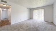 Located at 3006 Beech Grove Ct in Jeffersonville, Indiana, this single-story home offers three bedrooms, two bathrooms, and a practical, well-organized layout. The interior features a neutral color palette throughout, with white walls that create a clean and bright atmosphere.

The living area is carpeted and features a textured ceiling, a ceiling fan with a light fixture, and a sliding glass door that fills the room with natural light and provides outdoor access. A hallway connects the main living spaces to the bedrooms and bathrooms.

Each of the three bedrooms is finished with plush carpeting and white walls. The bedrooms include built-in closets with bifold doors, and several rooms feature windows with blinds that allow for natural light and outdoor views. The spacious primary bedroom offers a comfortable footprint well-suited for a full bedroom suite.

The two bathrooms serve distinct functions: one includes a full tiled tub-and-shower surround with chrome fixtures and wood-look flooring, while the other features an all-white tiled walk-in shower. Both bathrooms maintain a clean, straightforward design.

A dedicated area with wood-look vinyl flooring includes utility hookups, adding practical functionality to the home. The kitchen connects naturally to the main living spaces, completing a cohesive and efficient floor plan.