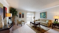 This single-story unit offers a thoughtfully arranged layout that maximizes its compact footprint across five distinct areas: a living room, bedroom, combined dining room and kitchen, bathroom, and hallway. The living room serves as the centerpiece of the unit, featuring plush carpeting, crown molding, and a large sliding glass door that floods the space with natural light while providing outdoor access. The open sightlines create an airy, welcoming atmosphere.

The combined kitchen and dining area is efficiently designed, with the kitchen showcasing warm honey-toned wood cabinetry, light countertops, a dishwasher, and tile flooring. Adjacent to the kitchen, the dining nook accommodates a small table and chairs, finished with crown molding details.

The bedroom offers a comfortable retreat with soft carpeting, a ceiling fan with light fixture, and a vaulted ceiling element that adds visual interest. A closet provides convenient storage within the room.

The bathroom features white tile surrounding the shower/tub combination, tile flooring, and a wood-toned vanity with a light countertop. A hallway connects the spaces, contributing to the unit's cohesive and functional flow.