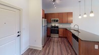 Located at 1100 Euclid Ave in Charlotte, NC's vibrant Dilworth neighborhood, this single-floor residence offers a thoughtfully designed layout with contemporary finishes throughout. The kitchen is a standout feature, equipped with rich warm-toned cabinetry, a subway tile backsplash, stainless steel appliances including a refrigerator, range, and microwave, and dark granite countertops. A peninsula with pendant lighting and an undermount sink adds both functionality and style, making it ideal for cooking and casual dining. The living area is bright and open, benefiting from multiple windows that invite natural light and provide access to an outdoor space through a glass door. Hardwood-style plank flooring flows through the main living areas, lending a clean, modern aesthetic. The bedroom is a comfortable retreat featuring plush carpet, a ceiling fan, and a window for natural light. The bathroom is well-appointed with a granite-topped vanity with rich wood cabinetry, a tub-shower combination with tiled surround, and hardwood-style flooring that ties the space together cohesively. Track lighting and ceiling fans are present throughout, enhancing both illumination and comfort in this efficiently planned Charlotte residence.