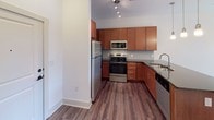 Located at 1100 Euclid Ave in Charlotte, NC's vibrant Dilworth neighborhood, this single-floor residence offers a thoughtfully designed layout with contemporary finishes throughout. The kitchen is a standout feature, equipped with rich warm-toned cabinetry, a subway tile backsplash, stainless steel appliances including a refrigerator, range, and microwave, and dark granite countertops. A peninsula with pendant lighting and an undermount sink adds both functionality and style, making it ideal for cooking and casual dining. The living area is bright and open, benefiting from multiple windows that invite natural light and provide access to an outdoor space through a glass door. Hardwood-style plank flooring flows through the main living areas, lending a clean, modern aesthetic. The bedroom is a comfortable retreat featuring plush carpet, a ceiling fan, and a window for natural light. The bathroom is well-appointed with a granite-topped vanity with rich wood cabinetry, a tub-shower combination with tiled surround, and hardwood-style flooring that ties the space together cohesively. Track lighting and ceiling fans are present throughout, enhancing both illumination and comfort in this efficiently planned Charlotte residence.