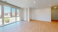 Located on the ninth floor at 8605 Cameron St in Silver Spring, Maryland, this two-bedroom, two-bathroom residence offers a thoughtfully designed single-level layout with a clean, modern aesthetic. Light-toned hardwood flooring runs throughout the main living areas and bedrooms, complementing the crisp white walls and bright, airy atmosphere.

The spacious living room is a standout feature, highlighted by floor-to-ceiling windows that frame sweeping views of the Silver Spring skyline, flooding the space with natural light. Recessed lighting adds a polished finish to the open layout. A well-defined hallway connects the living area to the private quarters, providing a clear and functional flow through the home.

The primary bedroom is generously sized, featuring large windows with city views and ample room for a full furniture arrangement. The second bedroom offers a comfortable, versatile space suitable for guests or a home office. Both rooms benefit from the same consistent light wood flooring and neutral palette.

Each of the two bathrooms showcases stylish, contemporary finishes, including white subway tile surrounds in the shower-tub combinations and distinctive dark herringbone-patterned tile flooring. White vanities with marble-style countertops complete the refined look. The kitchen and hallway round out the efficient and well-organized floor plan of this modern Silver Spring residence.