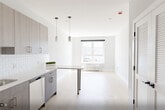 Unit 508 at 1213–1221 Broad St offers a thoughtfully designed one-bedroom, one-bathroom layout with a clean, contemporary aesthetic. Light hardwood flooring runs throughout the space, creating a warm and cohesive feel. The kitchen is a standout feature, outfitted with sleek, two-toned wood cabinetry extending to the ceiling for ample storage, a white subway tile backsplash, and light quartz countertops. Stainless steel appliances — including a refrigerator, range, over-the-range microwave, and dishwasher — complement the modern design, while a matte black faucet adds a refined contrast. The bedroom is a well-proportioned retreat bathed in natural light from a large window with urban views and fitted with a wall-mounted PTAC unit for climate control. Neutral gray walls and light flooring lend the room a calm, airy quality. The bathroom continues the modern theme with large-format tile flooring, dark wood vanity cabinetry, matte black hardware and fixtures, and a tub-shower combination accented with vertically tiled surround walls. Throughout the unit, clean lines and a restrained color palette create a polished, move-in-ready living environment.