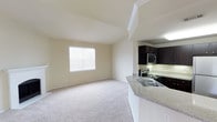 This single-floor residence offers a well-designed open-concept layout that connects the living and kitchen areas seamlessly. The living room features vaulted ceilings that enhance the sense of space, neutral-toned carpet flooring, and a large window that invites natural light. A white-mantled fireplace serves as a focal point, adding a classic, welcoming element to the room.

The kitchen is thoughtfully appointed with dark espresso cabinetry, granite-style countertops, and a full suite of stainless steel appliances, including a refrigerator, electric range, and over-the-range microwave. A peninsula with a built-in sink and breakfast bar creates a functional division between the kitchen and living space, ideal for casual dining or entertaining.

The bedrooms are carpeted and generously sized, each equipped with a ceiling fan and windows fitted with blinds for light control and privacy. The neutral wall tones throughout create a clean, cohesive aesthetic.

The bathroom includes a soaking tub with shower, a toilet, dark upper cabinetry for storage, and granite-style countertop detailing, maintaining the consistent design language found throughout the residence.