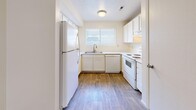 Located in Millcreek, Utah, this single-floor, 2-bedroom, 2-bathroom unit offers a functional and well-organized layout. The U-shaped kitchen features white cabinetry, white appliances including a refrigerator, dishwasher, and range, complemented by a window above the sink that brings in natural light. Wood-look flooring runs throughout the kitchen, while neutral carpet covers the living and bedroom areas.

The living room is a comfortable, open space anchored by a sliding glass door with vertical blinds, allowing natural light and outdoor access. Both bedrooms are carpeted and include ceiling fans with light fixtures and windows for ventilation and natural light. The primary bedroom is a well-proportioned space, while the second bedroom features a sliding double-door closet. A hallway connects the main living areas to both bedrooms and bathrooms.

The two bathrooms each feature warm wood-toned vanity cabinetry, single-basin sinks, and wood-look flooring. One bathroom includes a shower/tub combination, while the other offers a walk-in style shower. The overall aesthetic is clean and neutral throughout, with light-colored walls and simple, practical finishes that provide a move-in-ready feel.