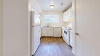 Located in Millcreek, Utah, this single-floor, 2-bedroom, 2-bathroom unit offers a functional and well-organized layout. The U-shaped kitchen features white cabinetry, white appliances including a refrigerator, dishwasher, and range, complemented by a window above the sink that brings in natural light. Wood-look flooring runs throughout the kitchen, while neutral carpet covers the living and bedroom areas.

The living room is a comfortable, open space anchored by a sliding glass door with vertical blinds, allowing natural light and outdoor access. Both bedrooms are carpeted and include ceiling fans with light fixtures and windows for ventilation and natural light. The primary bedroom is a well-proportioned space, while the second bedroom features a sliding double-door closet. A hallway connects the main living areas to both bedrooms and bathrooms.

The two bathrooms each feature warm wood-toned vanity cabinetry, single-basin sinks, and wood-look flooring. One bathroom includes a shower/tub combination, while the other offers a walk-in style shower. The overall aesthetic is clean and neutral throughout, with light-colored walls and simple, practical finishes that provide a move-in-ready feel.