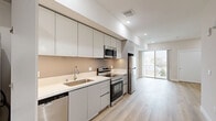 Located at 825 S Coronado St in Los Angeles, this modern studio offers a thoughtfully designed single-floor layout that maximizes every square foot. The open-concept kitchen and living area form the heart of the space, featuring light hardwood flooring that flows seamlessly throughout. The contemporary kitchen is outfitted with flat-front, matte gray cabinetry extending to the ceiling for ample storage, crisp white quartz countertops, and a full suite of stainless steel appliances including a dishwasher, electric range, built-in microwave, and refrigerator. Recessed lighting illuminates the space, complementing the clean, minimalist aesthetic defined by neutral warm-white walls. The living area is open and airy, anchored by a large sliding glass door that leads to a private balcony with outdoor views, filling the room with natural light. A dedicated closet with sliding doors provides convenient storage. The bathroom continues the modern palette with light hardwood-style flooring, a white vanity, and clean white walls. The overall ambiance is bright, fresh, and contemporary, making efficient use of its well-planned layout.