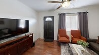 Located on Grover Ave in the heart of Austin, TX, this compact yet efficiently designed single-story home offers three bedrooms, one bathroom, a living room, kitchen, and connecting hallway. Rich hardwood flooring runs throughout, lending warmth and continuity to the entire layout.

The living room serves as a welcoming entry point, featuring a ceiling fan, natural light from multiple windows with gray curtains, and a comfortable seating arrangement centered around a media console. The space flows naturally into the rest of the home via a central hallway.

The kitchen is equipped with stainless steel appliances — including a gas range, over-the-range microwave, and full-size refrigerator — complemented by taupe cabinetry and a modern sputnik-style light fixture. A window provides natural light to the workspace.

The primary bedroom accommodates a queen bed, ceiling fan, and dresser, with a connecting view down the hallway. A second bedroom comfortably fits two full beds with matching decor and ceiling fan. The third bedroom is a cozy, sunlit room with neutral curtains and a window chair.

The shared bathroom is finished with granite countertops, an arched vanity mirror, modern pendant lighting, and a shower-tub combination, offering a clean and stylish design.
